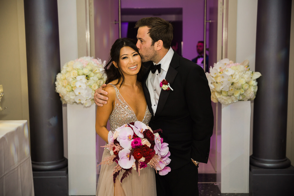 Destination wedding in Paris - Bride and groom kiss with wdding bouquet in hand