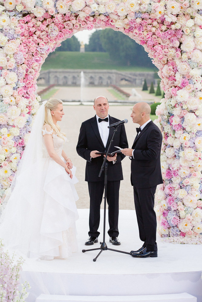 Bride and groom exchanging vows during wedding ceremony in the gardens of a French chateau near Paris